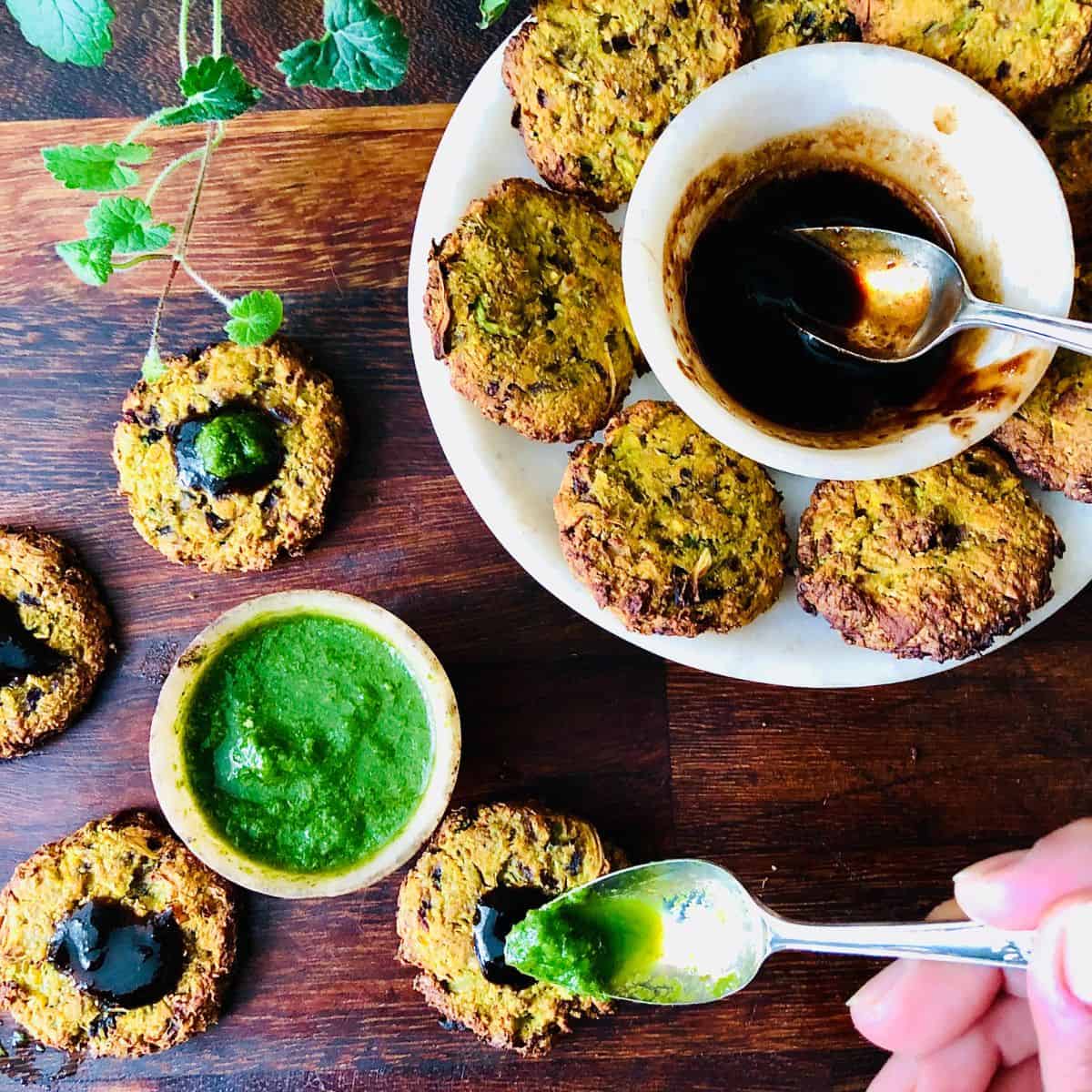 A plate containing broccoli fritters with a small dish of chutney in the middle