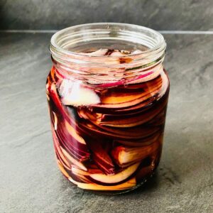 Close up of a jar of pickled red onion.