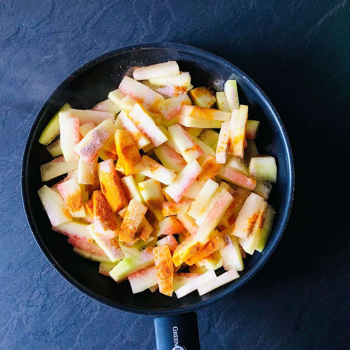 A frying pan containing watermelon rind recipe ingredients for Tarbooz Ki Sabzi