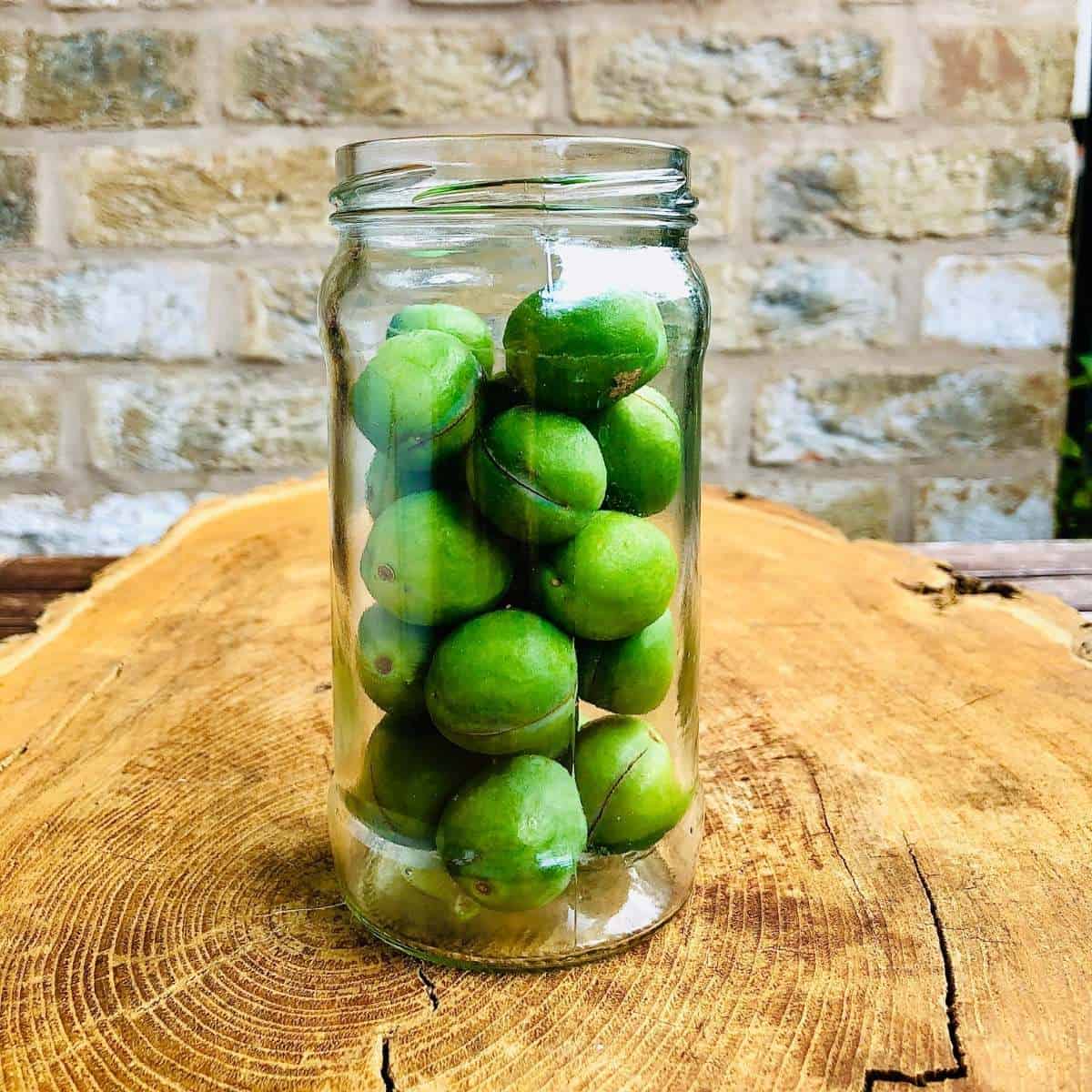 Close up of a jar containing tightly packed in unripe plums
