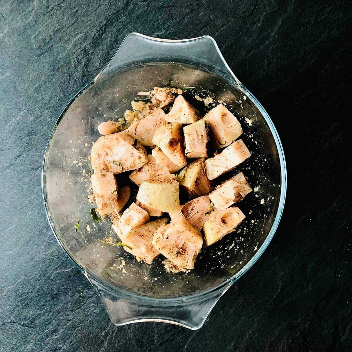 Glass bowl containing jackfruit pieces covered in a marinade, ready for cooking