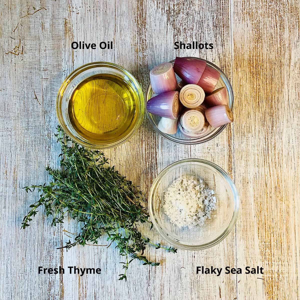 Prepared ingredients for confit shallots in small glass dishes. Annotated. Fresh thyme, flaky sea salt, olive oil and shallots.