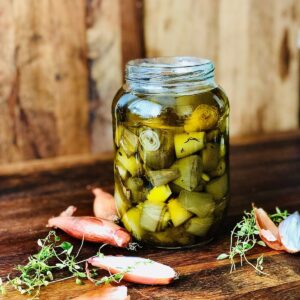 A jam jar containing confit shallots in olive oil.