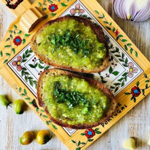 Two slices of toasted bread topped with green heirloom tomato pan con tomate.