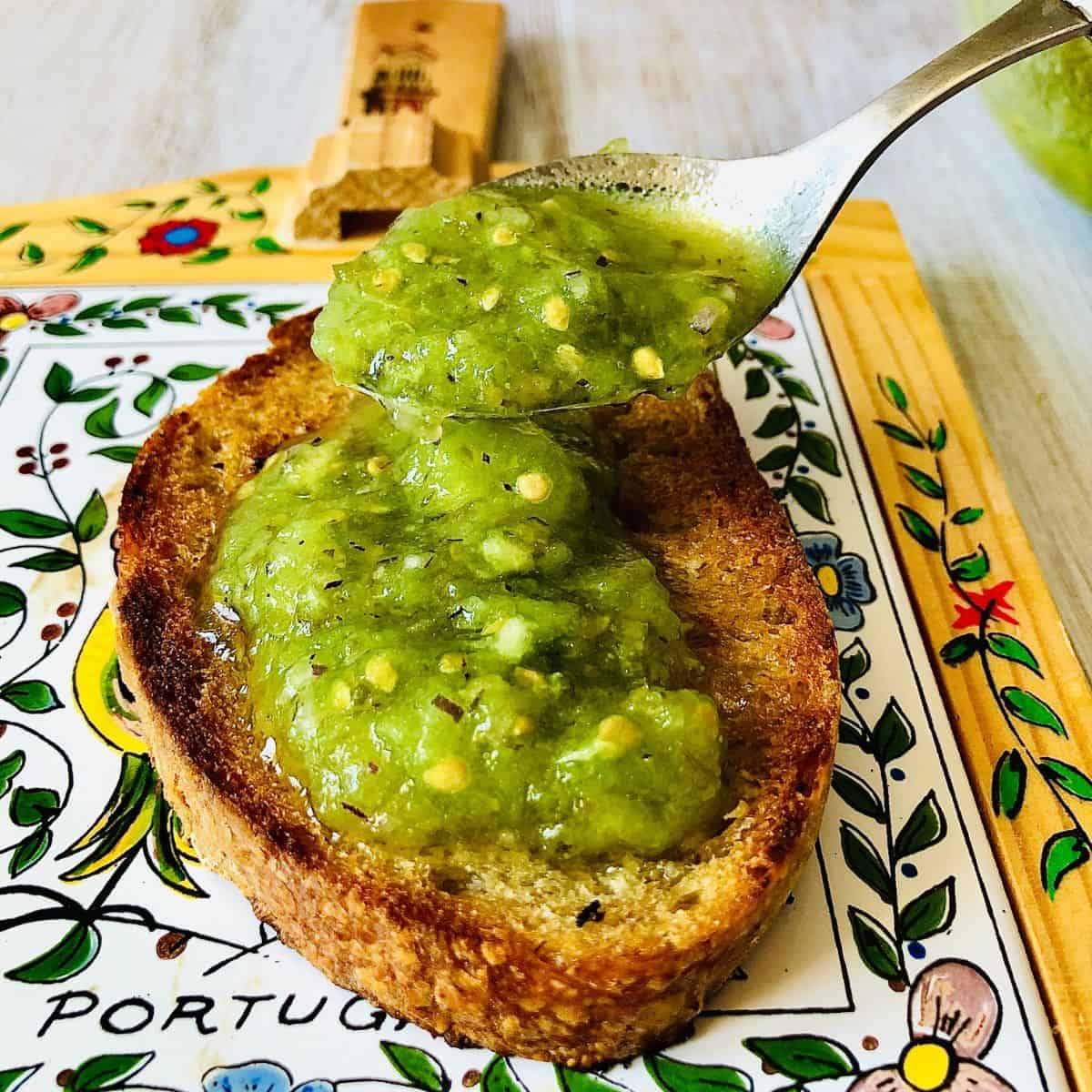 Close up of spooning green heirloom tomato pan con tomate onto a slice of sourdough bread