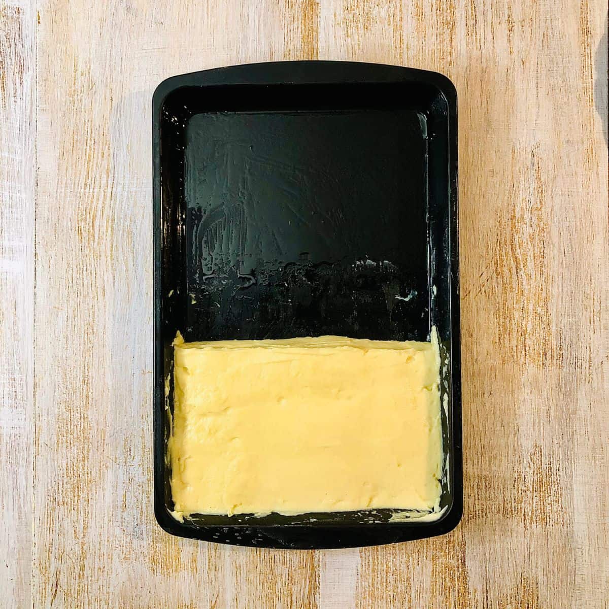 A slab of cooked gram flour paneer in a baking tray ready to set