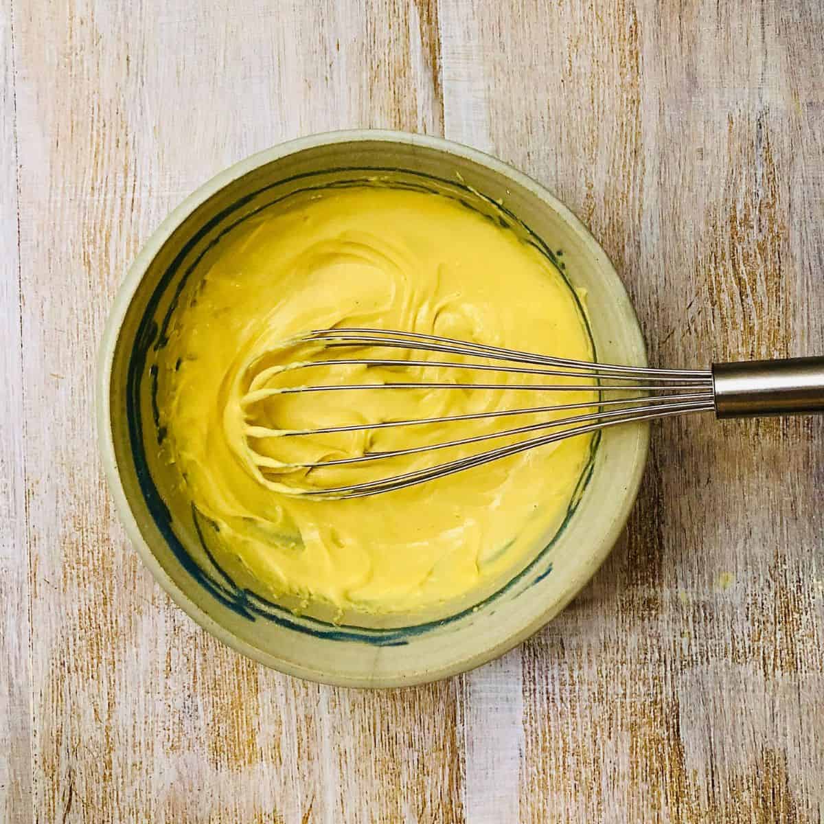 Thick gram flour paneer batter in a bowl with a whisk