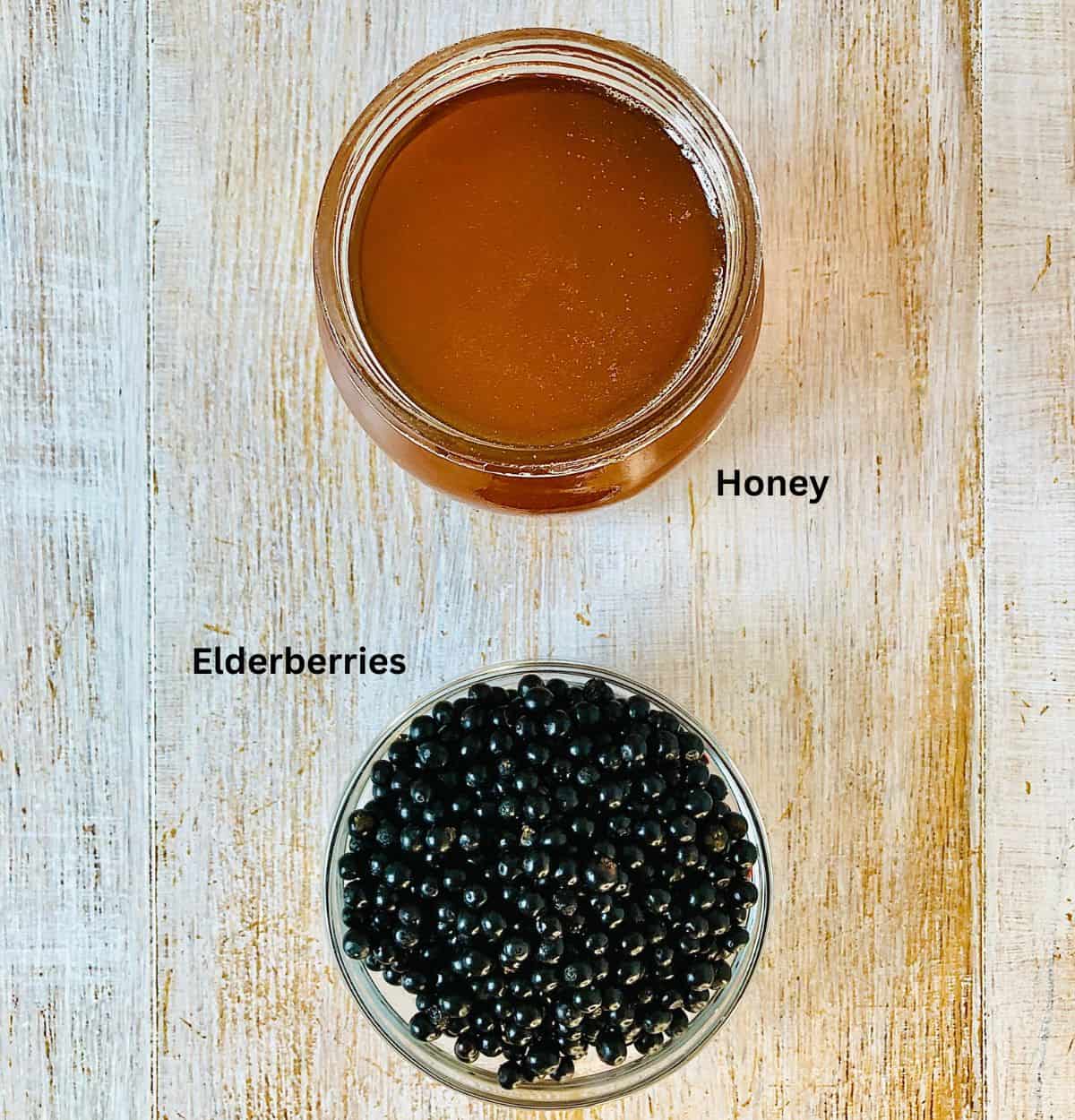 A jar containing honey and a small glass dish containing elderberries.