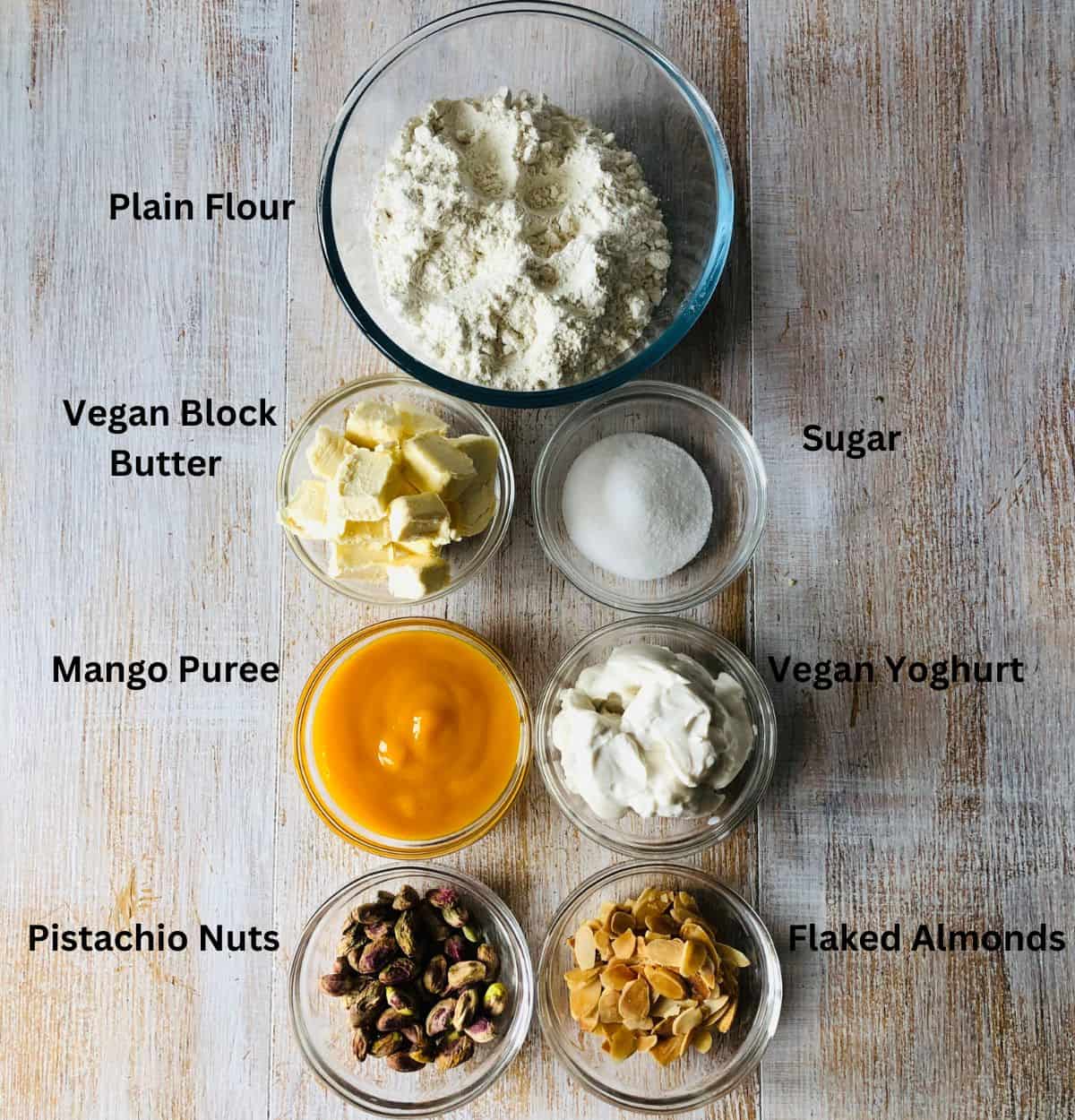 Ingredients for mango shrikand flavoured yoghurt tarts in small glass dishes.