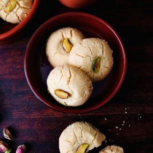 Close of three nankhatai biscuits in a small round ceramic dish.