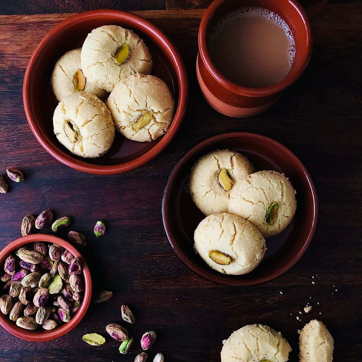 Two small, round ceramic dishes each containing three nankhatai biscuits.