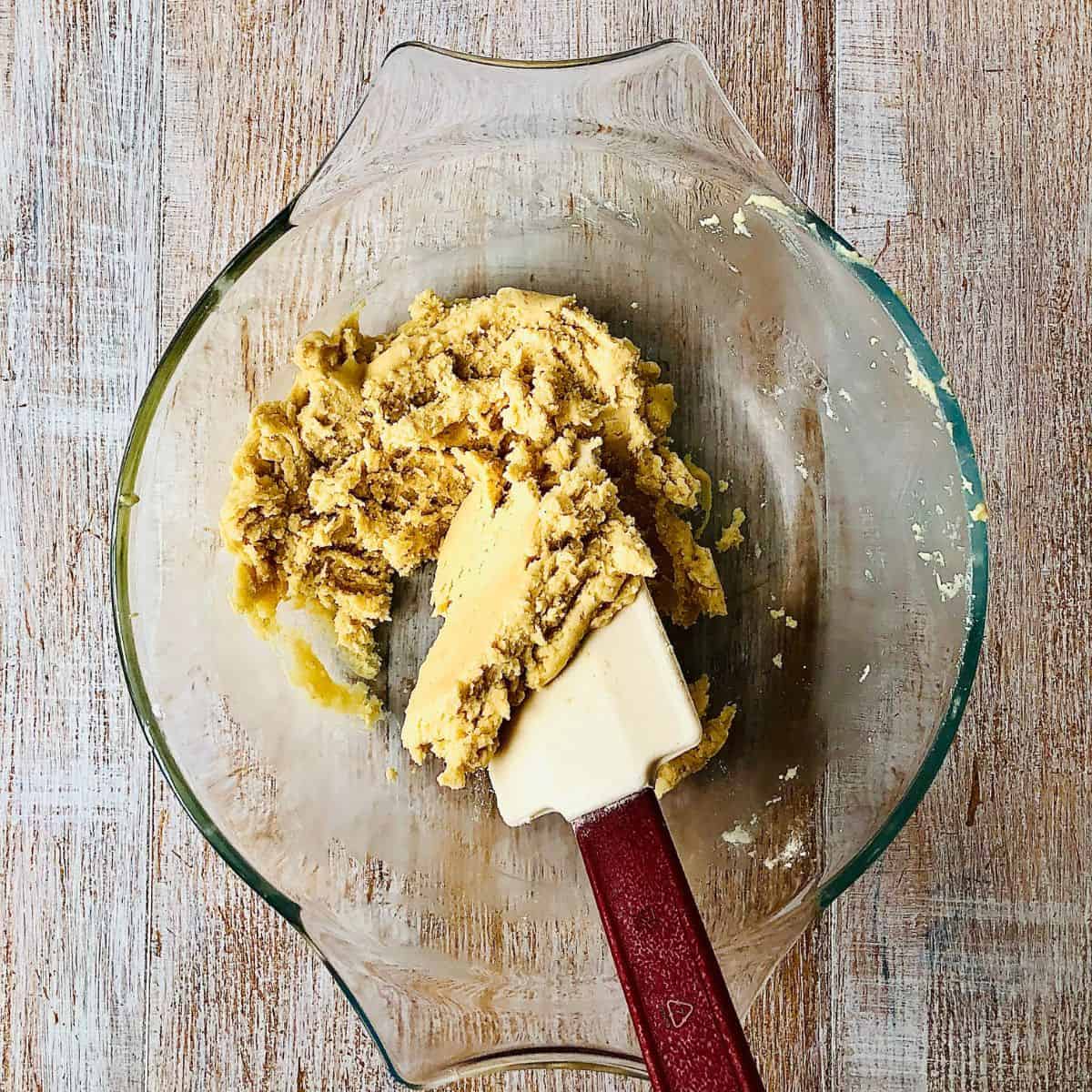 A glass bowl containing nankhatai biscuit dough mix with a spatula.