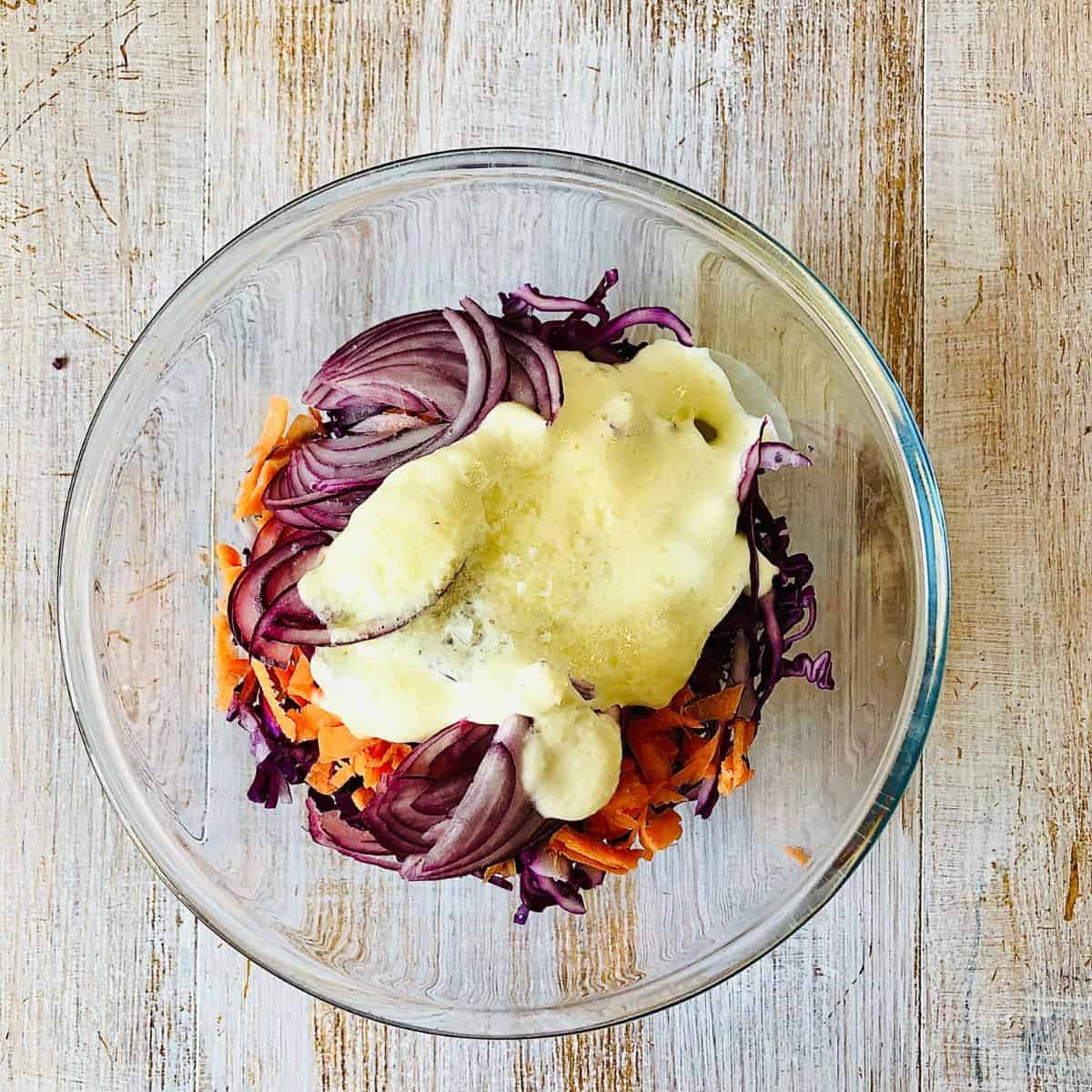 Ingredients for vegan coleslaw in a glass bowl ready to mix.