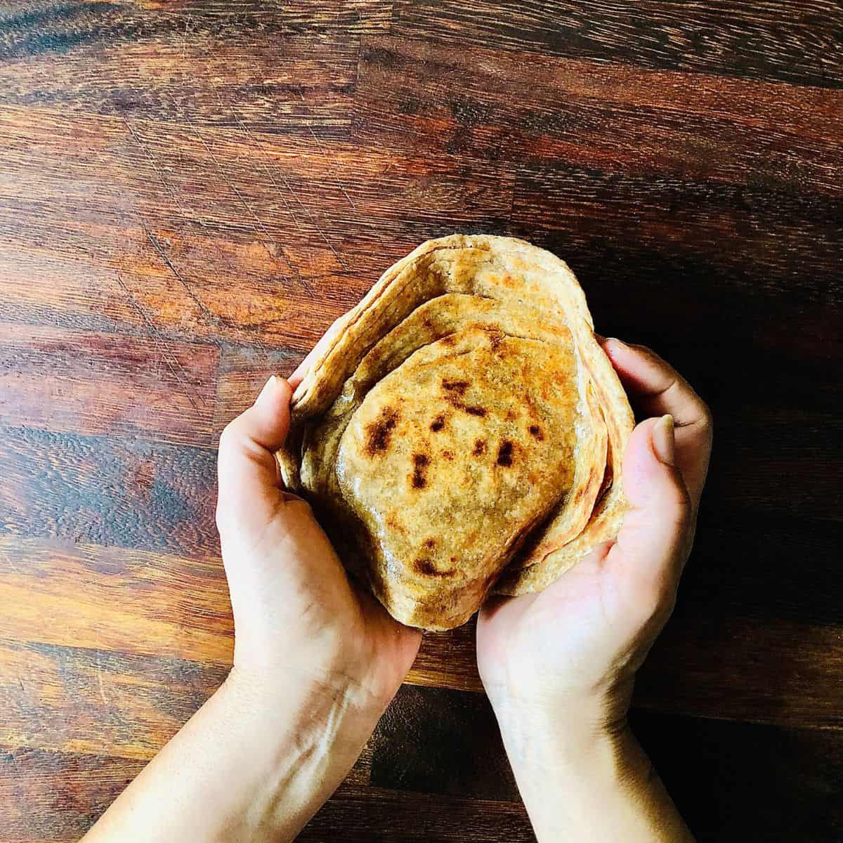 Laccha paratha held between two hands, showing the layers of the laccha paratha.