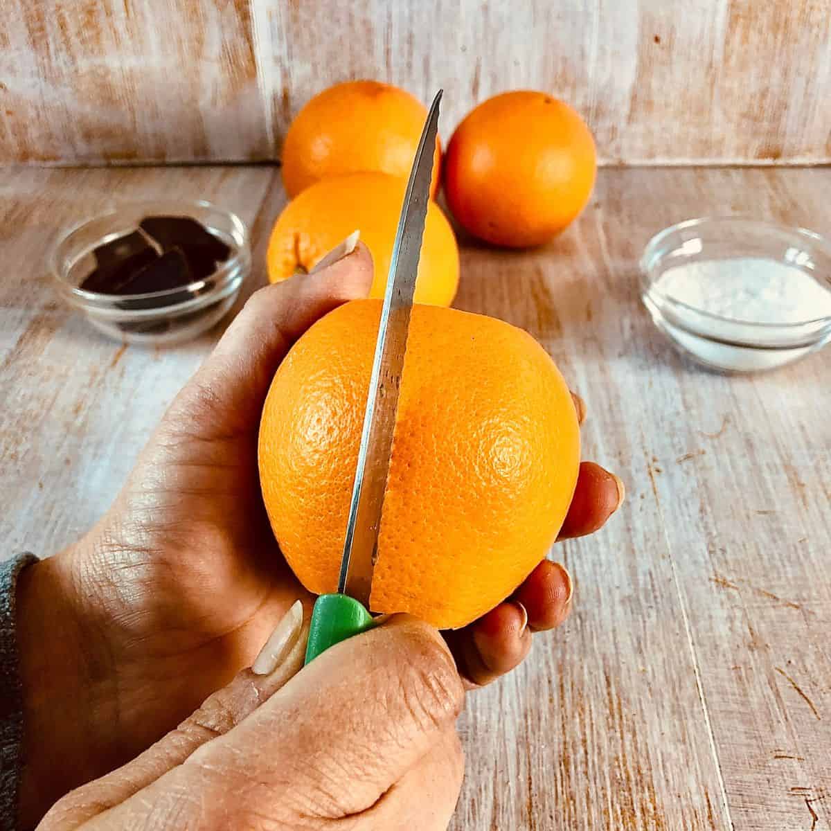 Close up of a knife scoring the peel of an orange.