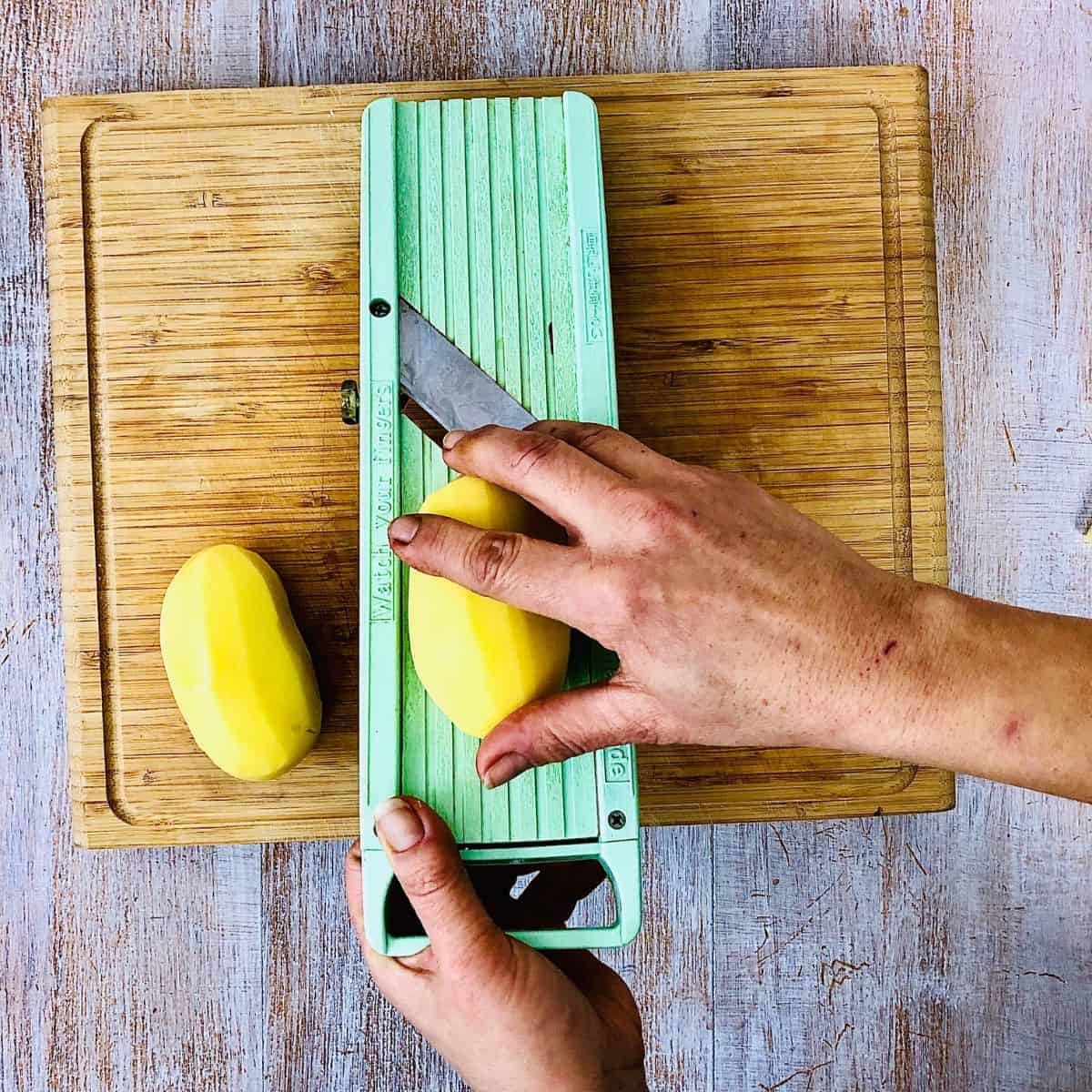 Slicing potatoes using a mandolin slicer.