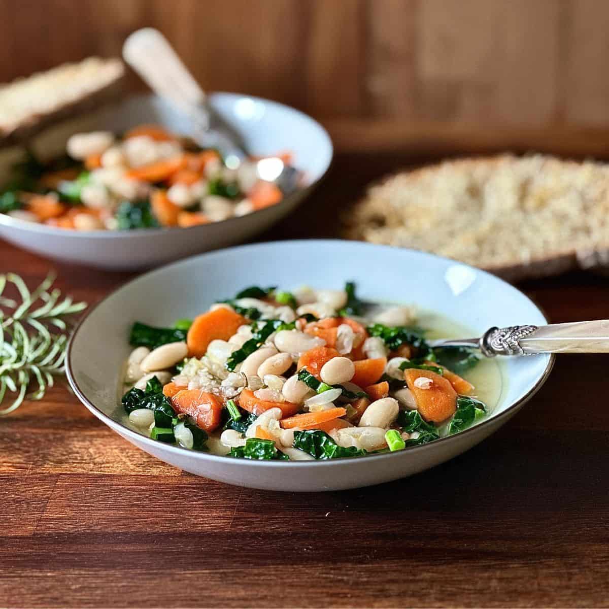 A serving bowl containing cannellini bean soup with cavolo nero and carrots.
