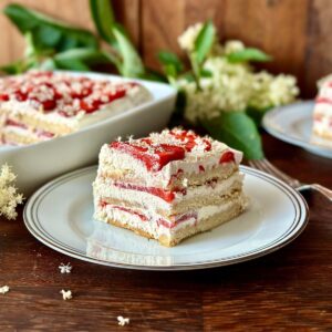 A slice of elderflower and strawberry cake on a small plate.