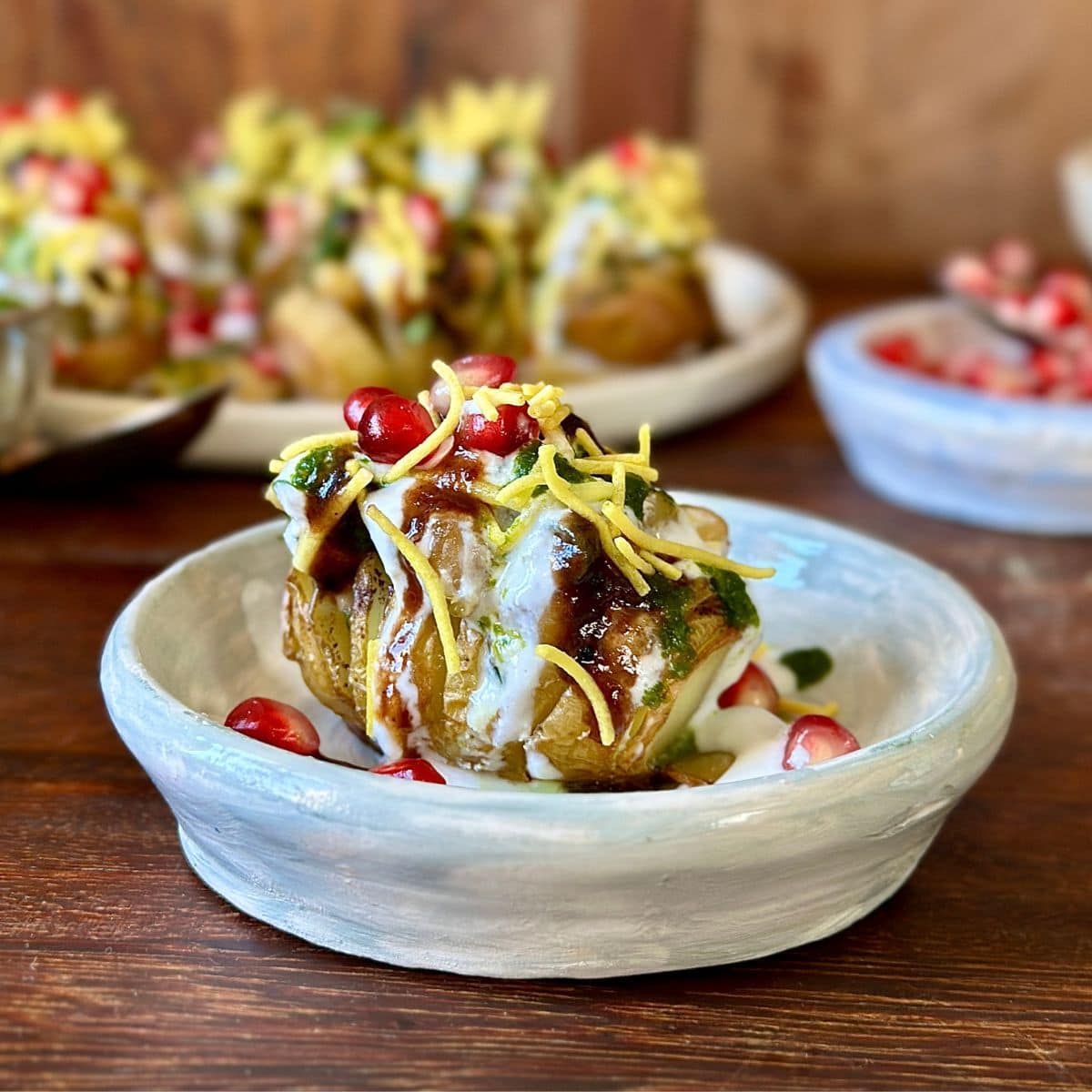 A small rustic dish containing a single hasselback potato matar ki chaat, ready to eat.