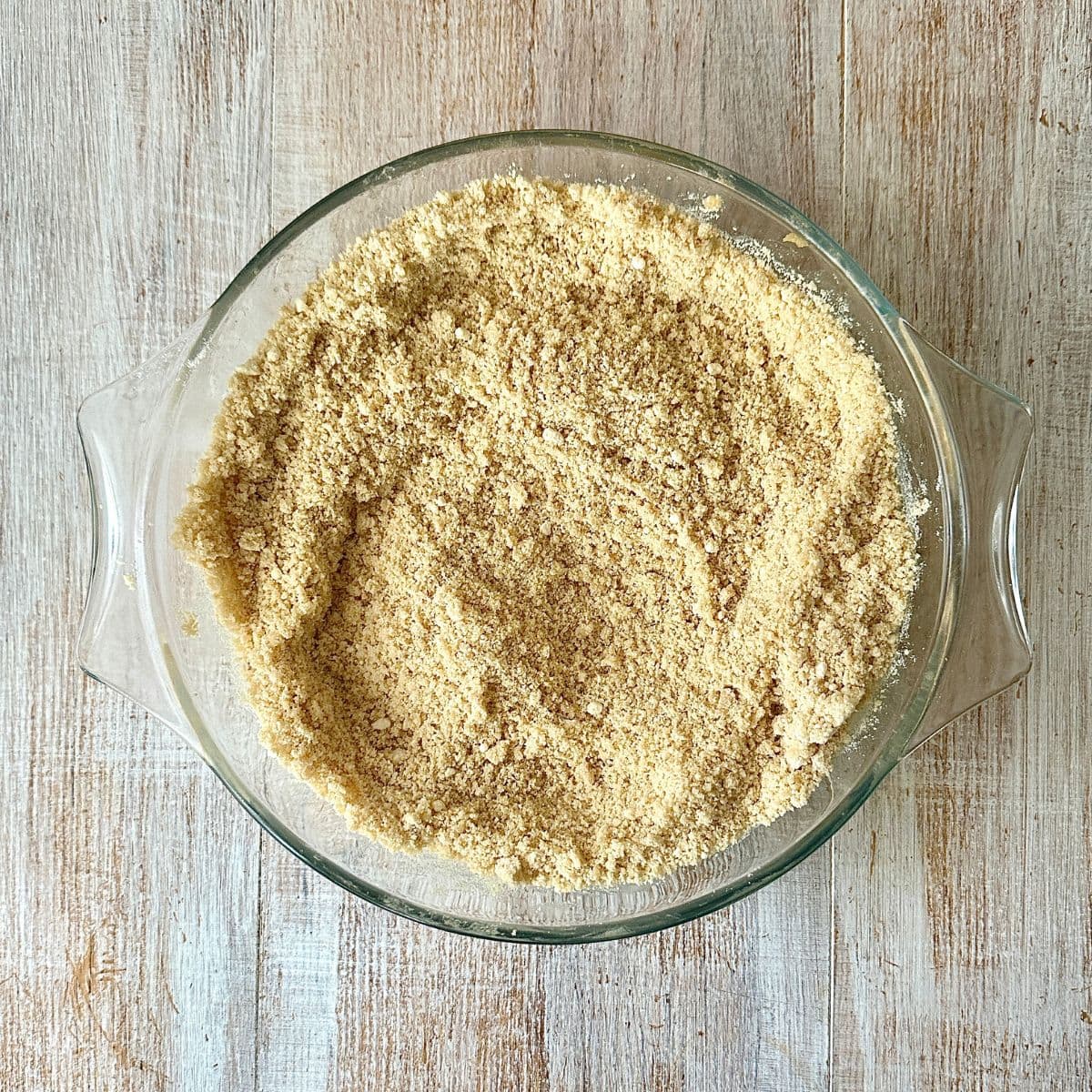 A glass dish containing crumbly Gulab Jamun Cookie dough mix.