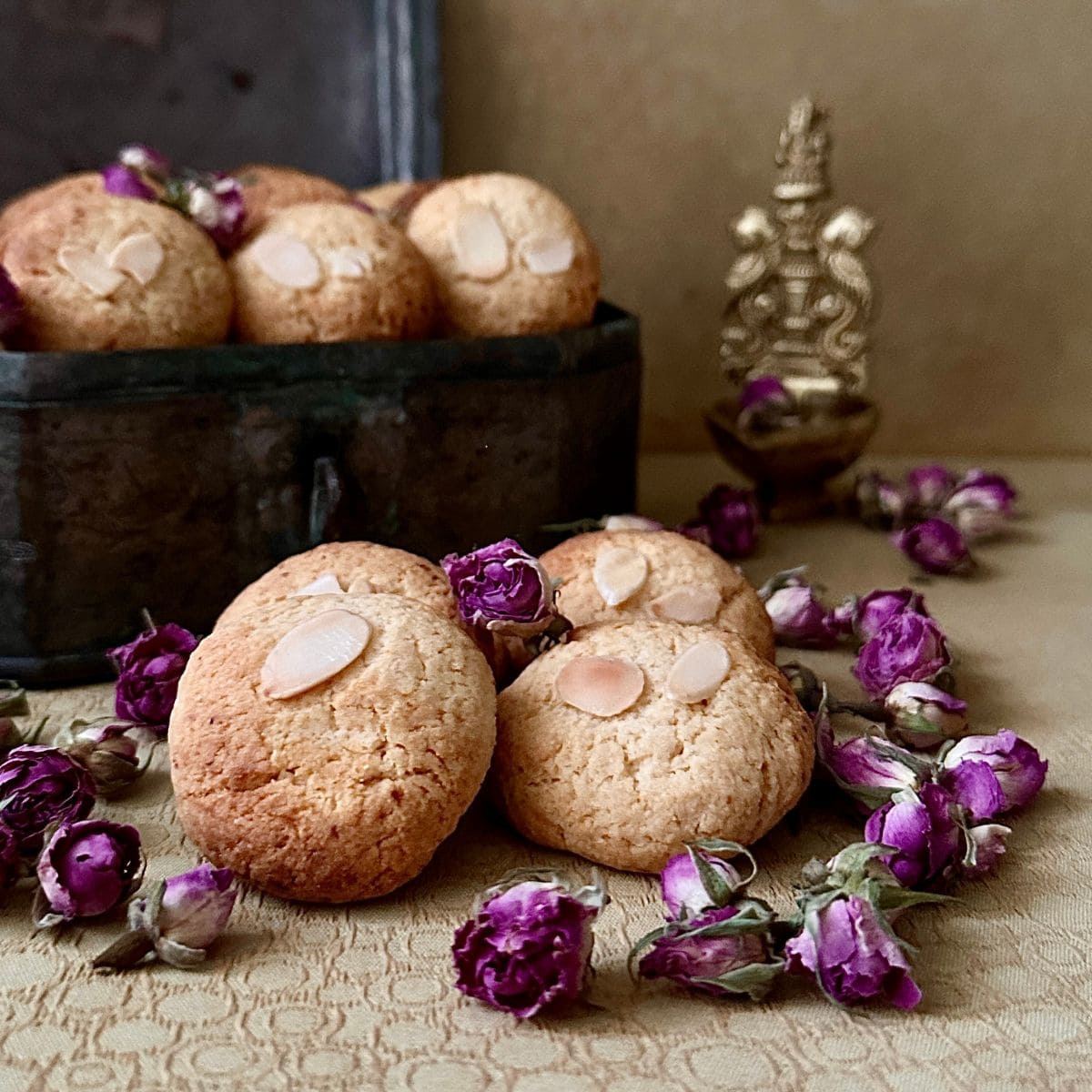Four Gulab Jamun cookies surrounded by dried rose heads.