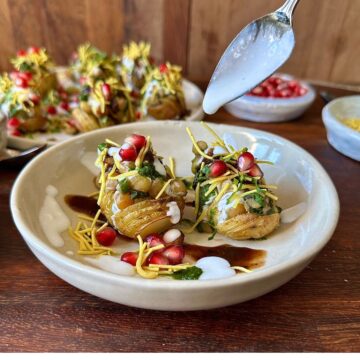 A white ceramic plate containing two hasselback potato matar ki chaat.