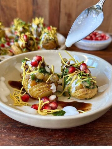 A white ceramic plate containing two hasselback potato matar ki chaat.