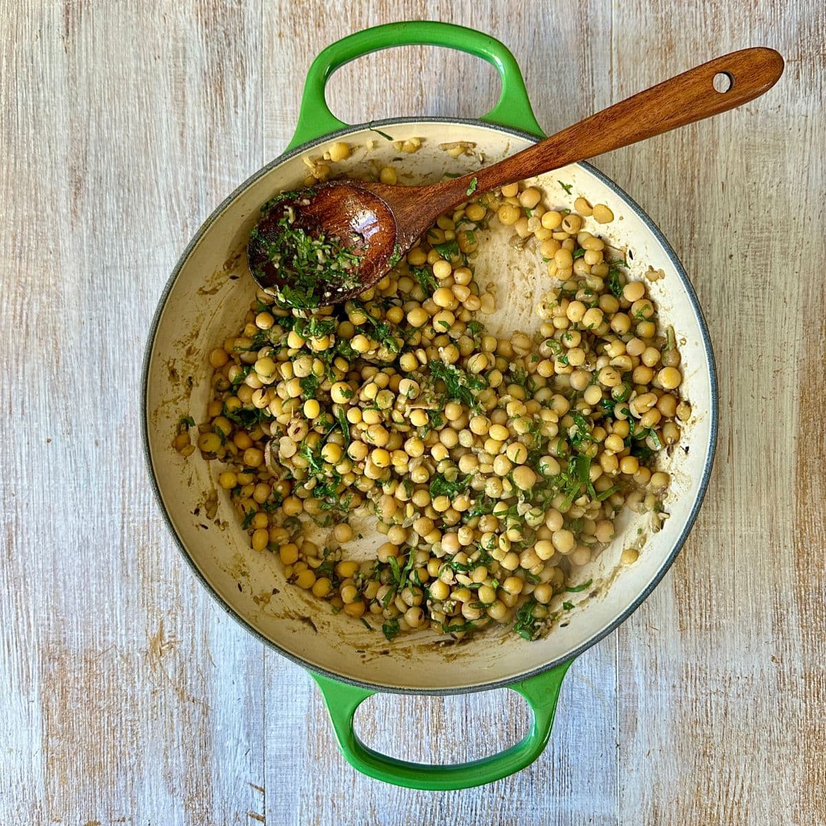 A large saucepan containing matar (spicy peas) mixture, with a wooden spoon in it.