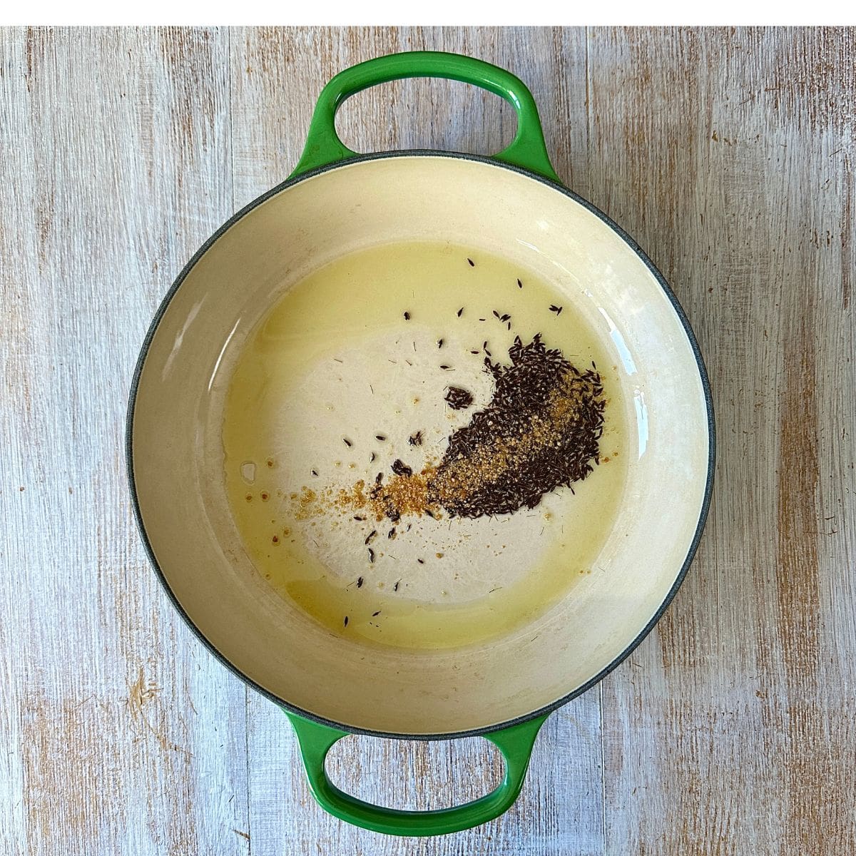 Large saucepan containing cumin seas and asafoetida frying in olive oil.