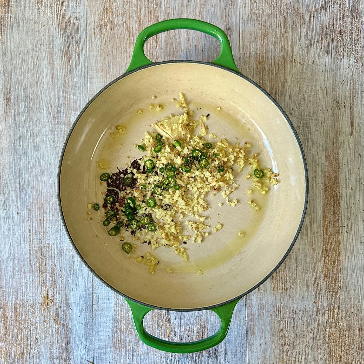 large saucepan containing cumin seeds, asafoetida, chopped green chilli and chopped ginger, frying in olive oil.