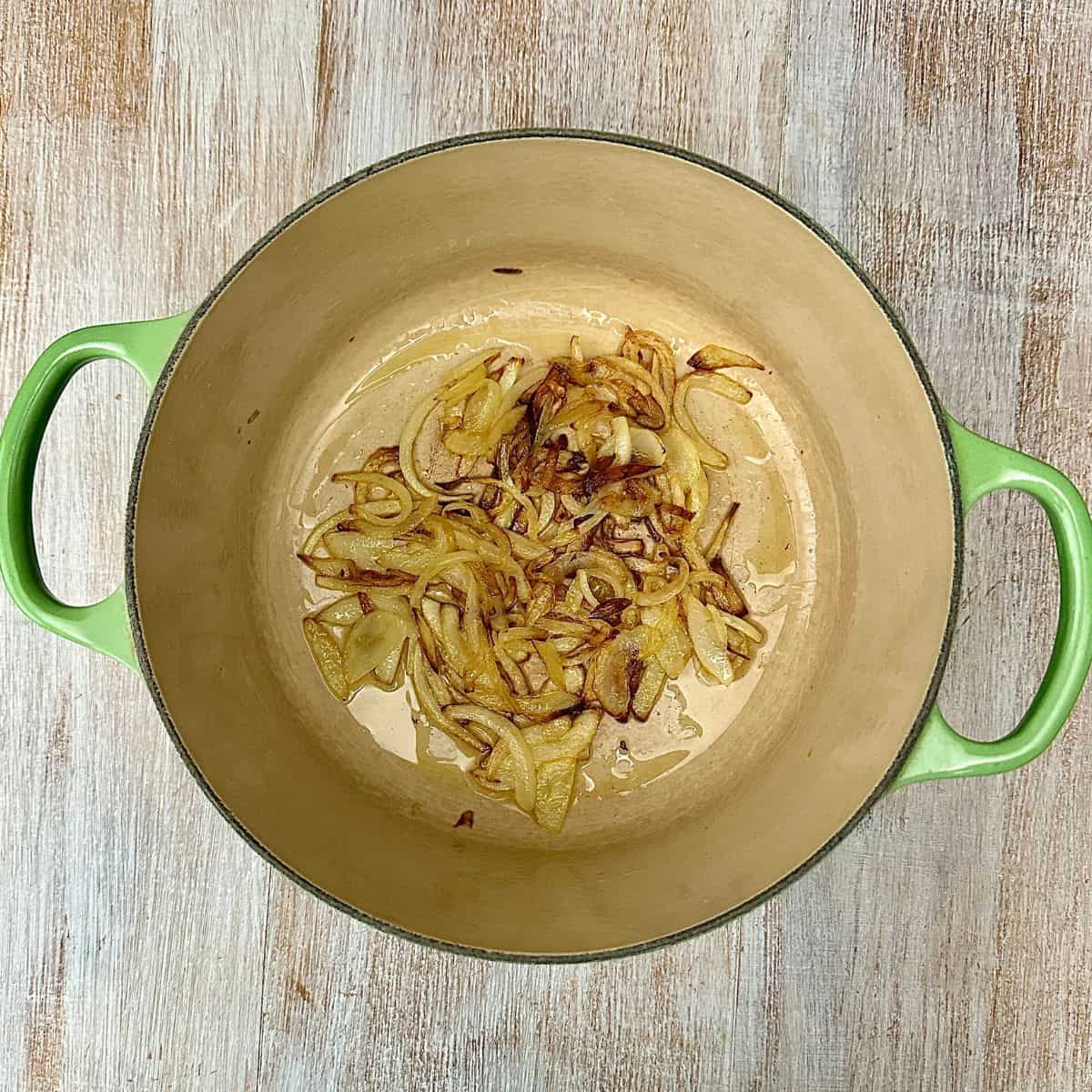 A large green pot containing caramelised sliced onion.
