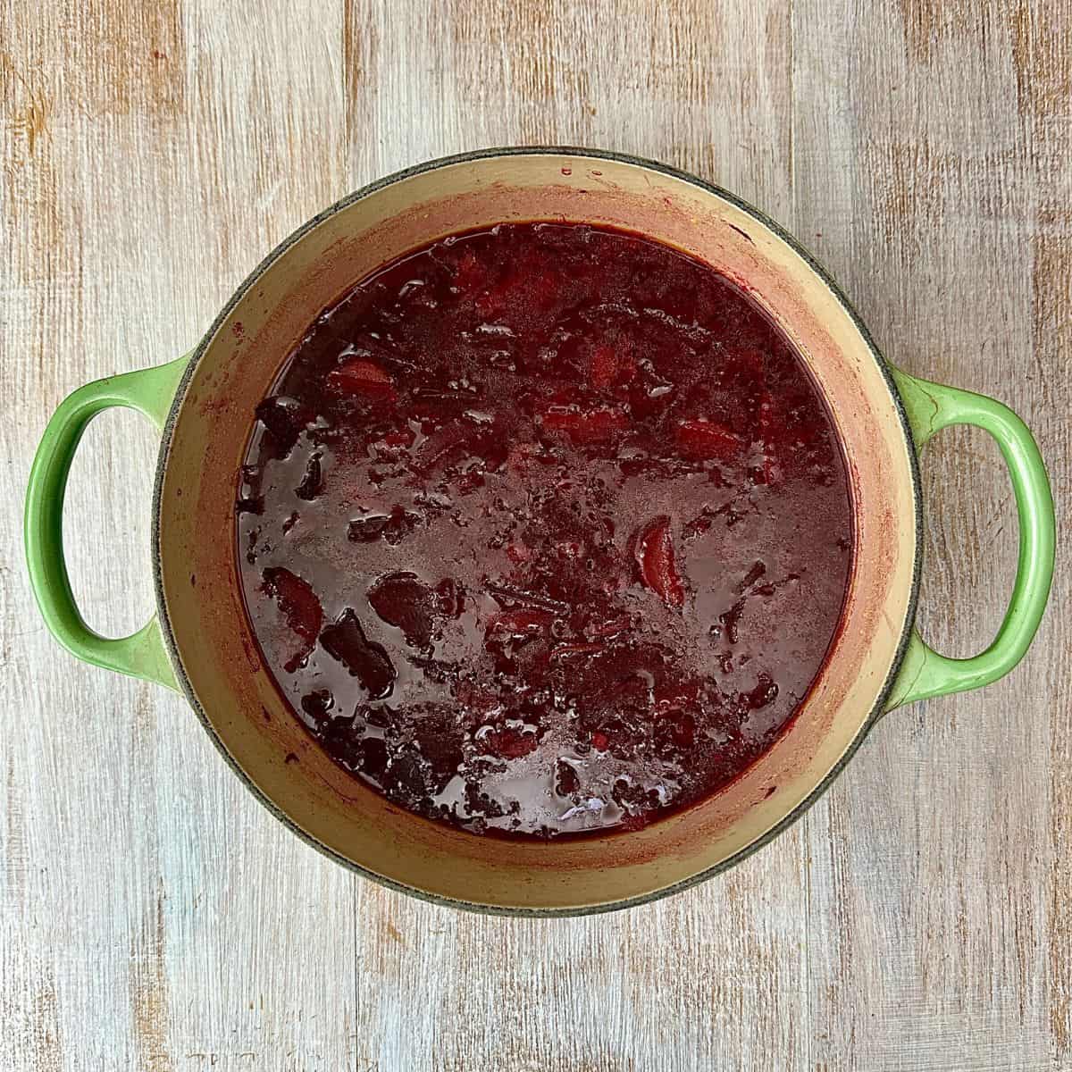 A large green pot containing cooked beetroot soup ingredients, ready to blend.