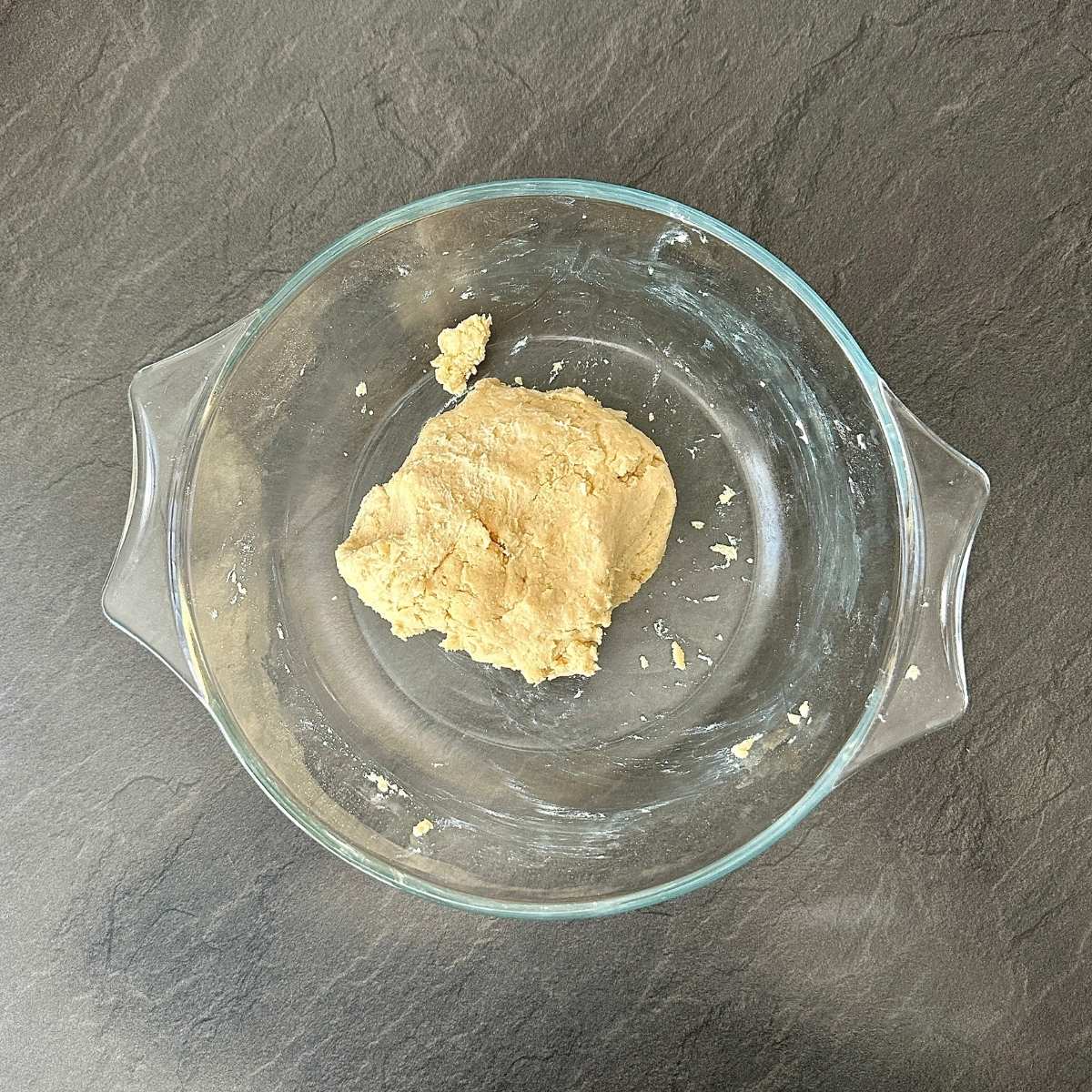 A glass bowl containing pumpkin galette dough.