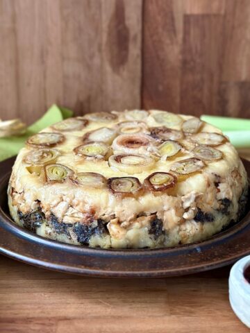 Vegan leek and mushroom Christmas bake on a brown ceramic plate.