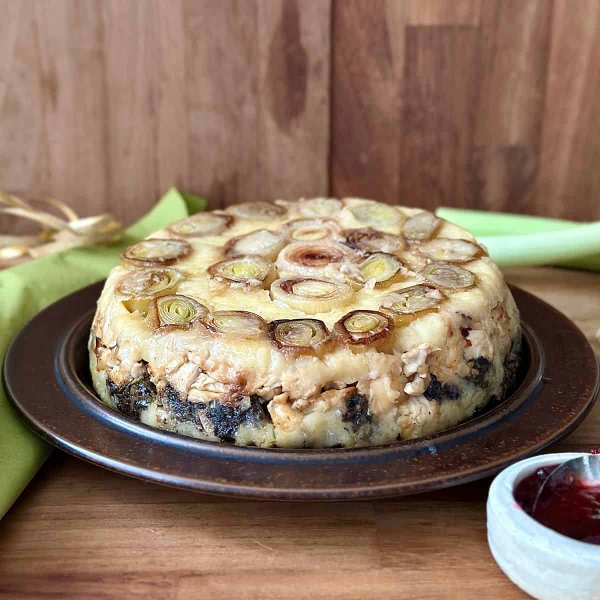 Vegan leek and mushroom Christmas bake on a brown ceramic plate.