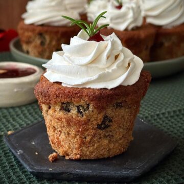 Close up of a vegan Christmas cupcake with Brandy frosting, sat upon a hexagonal slate coaster.