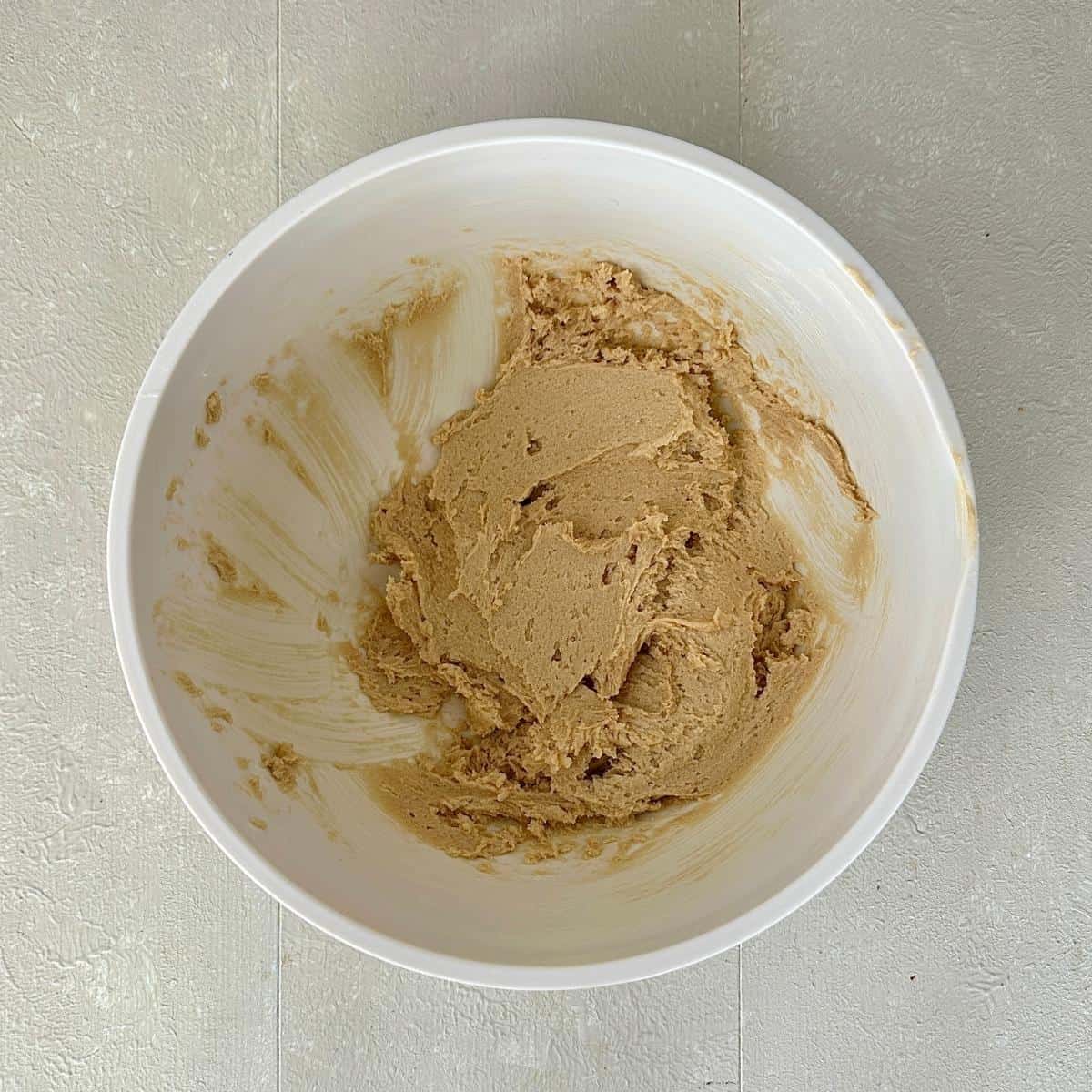 A white bowl containing creamed vegan butter and soft brown sugar for making vegan christmas cupcakes.