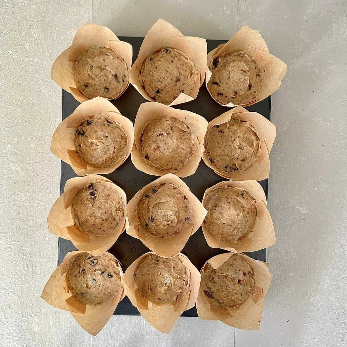 Nine paper cupcake cases containing vegan Christmas cupcake dough, ready to bake.