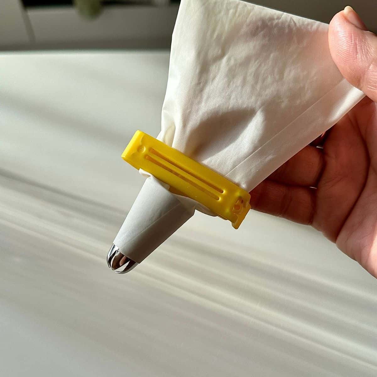 Close up of a hand holding a piping bag fitted with a star shaped nozzle.