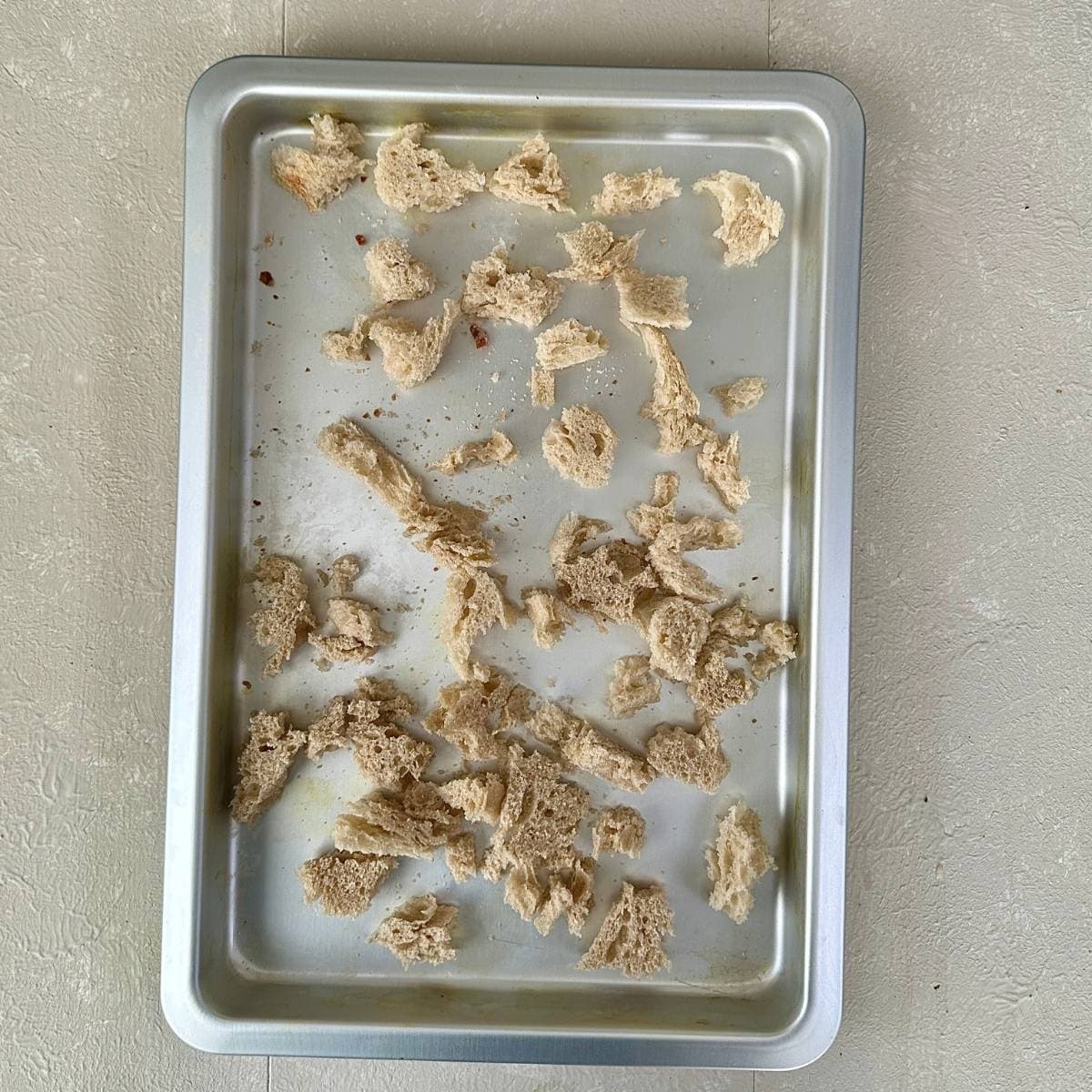 A baking tray containing pieces of torn up sourdough bread ready to dry-out.