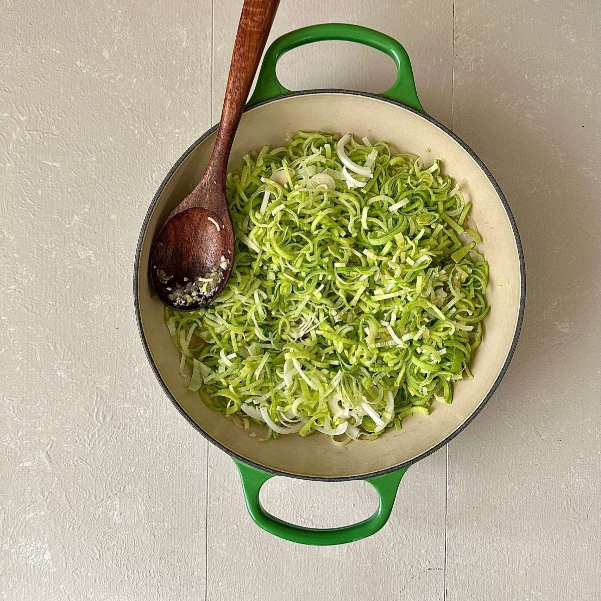 A large green pot containing leeks cut into small slices.