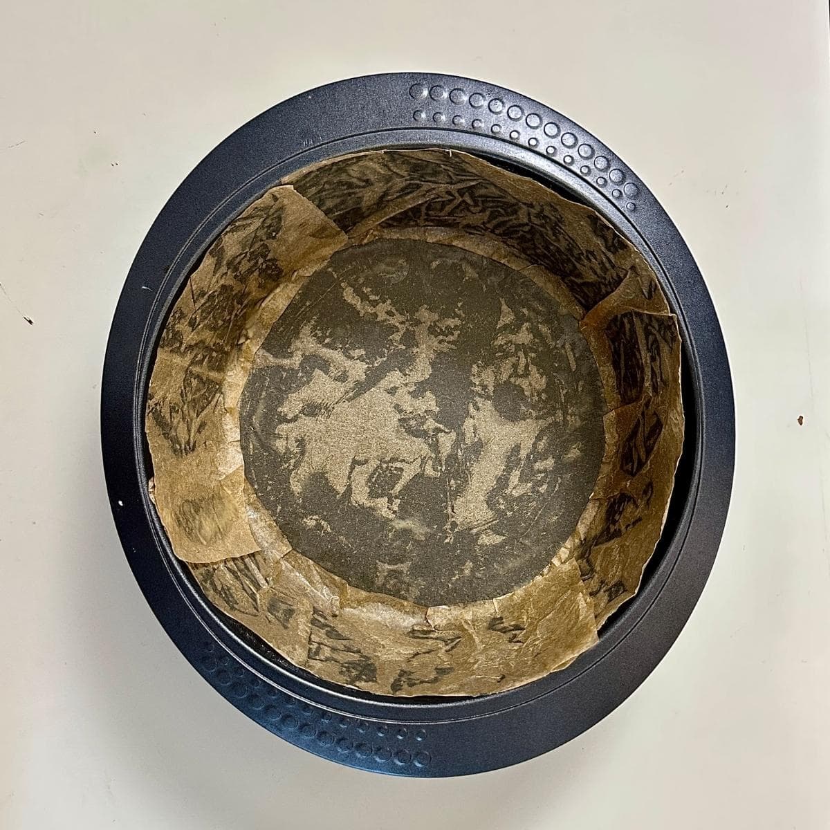 A round cake tin lined with parchment paper.