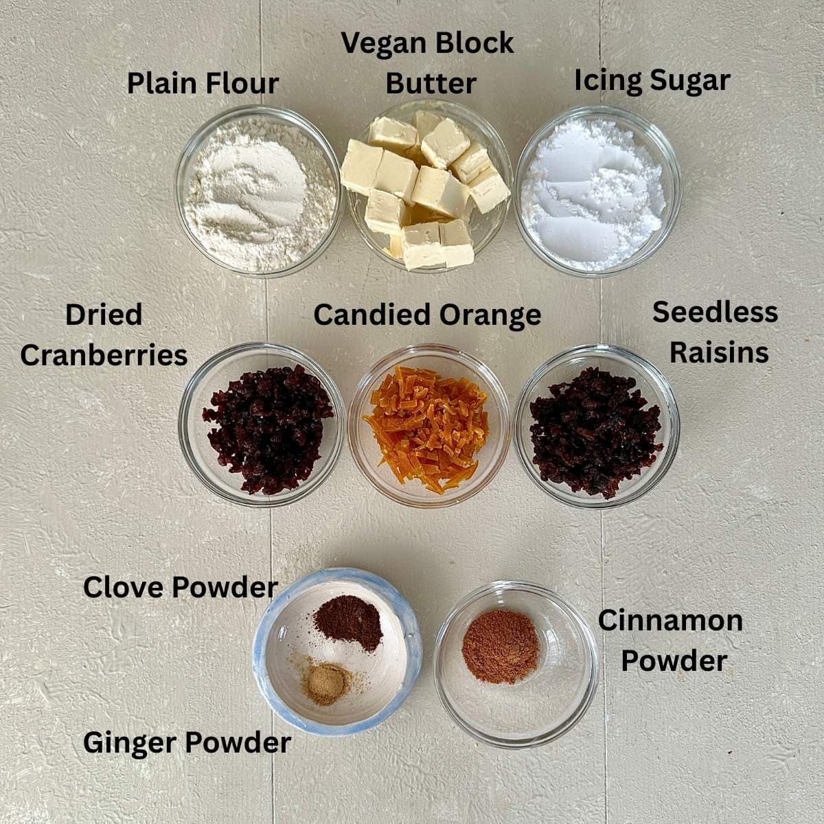 Prepared ingredients for vegan Christmas biscuits in small glass dishes. Annotated.