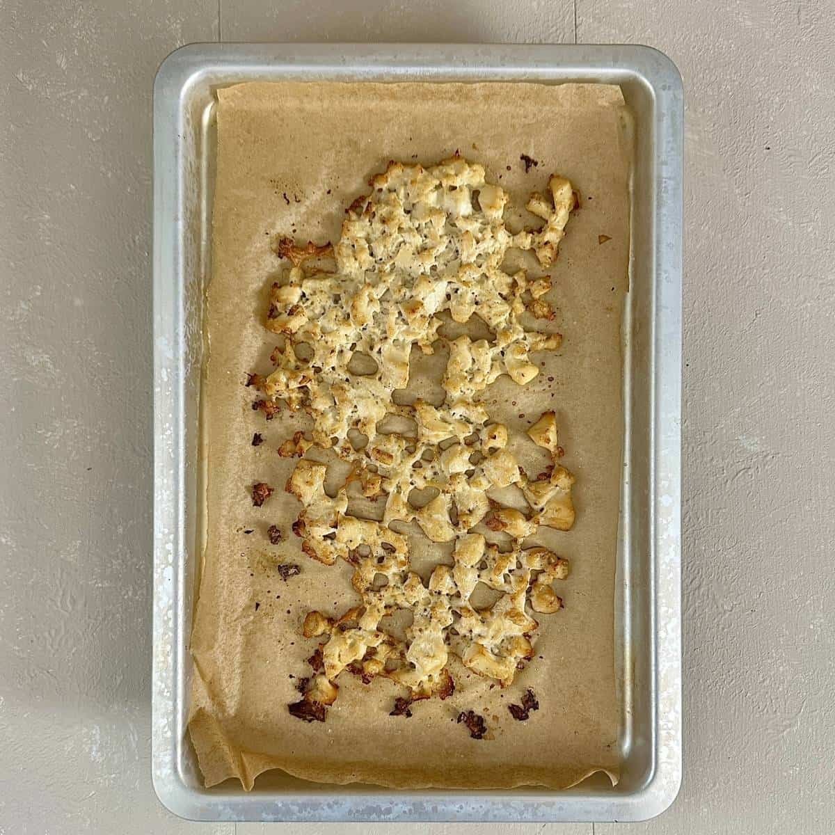 A baking tray lined with parchment paper containing chunks of firm tofu, browned after cooking.