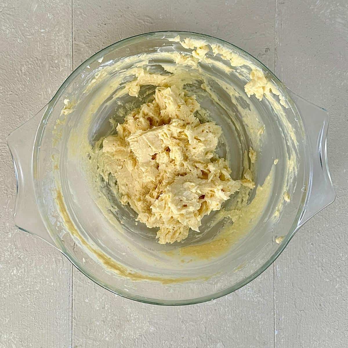 A glass bowl containing vegan butter and icing sugar mixed together for vegan Christmas biscuits.