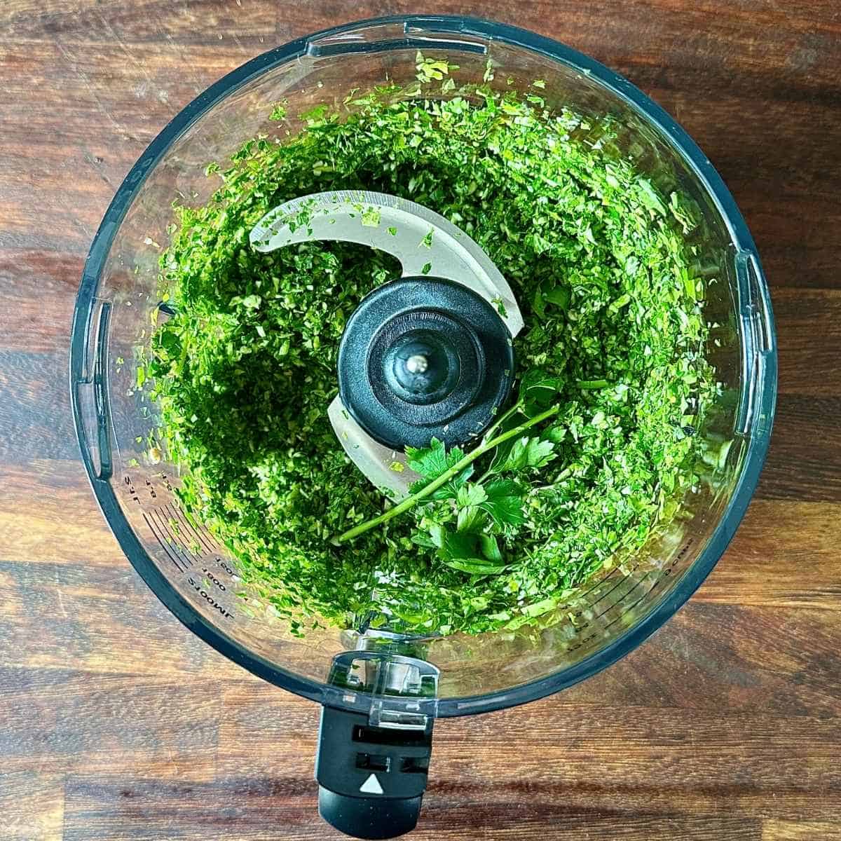 A blender jug containing Finley blended fresh parsley, coriander and mint.