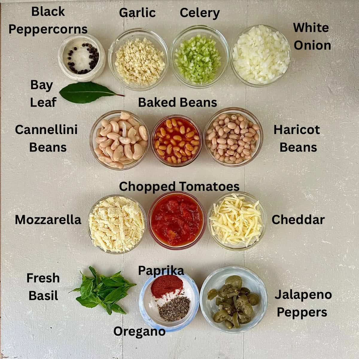 Prepared Ingredients for cheesy pizza beans arranged in small glass dishes. The ingredients are annotated.