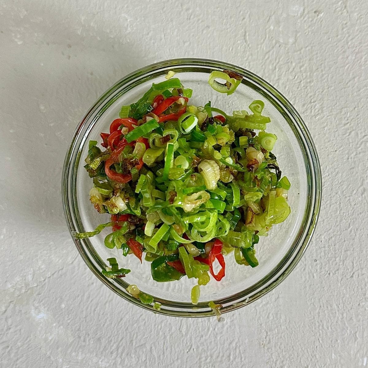 Fried slices of jalapeรฑo peppers and spring onion in a glass bowl. Garnish for leek and lentil soup.
