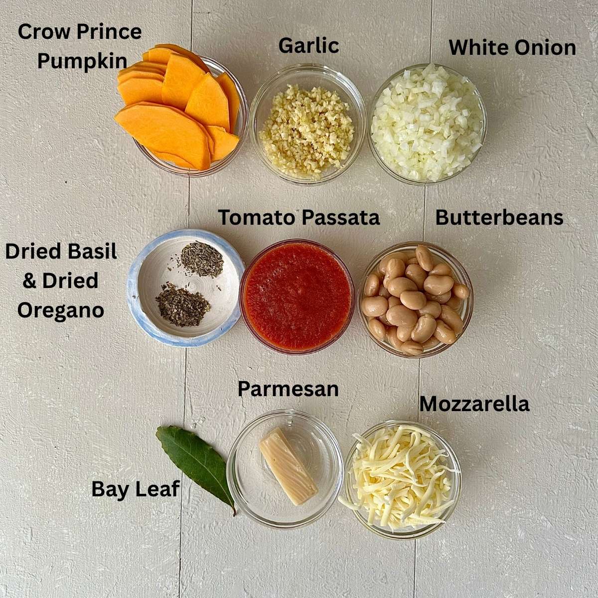 Prepared ingredients for pumpkin casserole in small glass dishes. Ingredients are annotated.