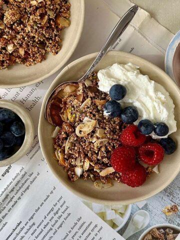 Homemade sugar free granola with almonds, seeds and popped amaranth in a bowl with yoghurt and fresh berries.